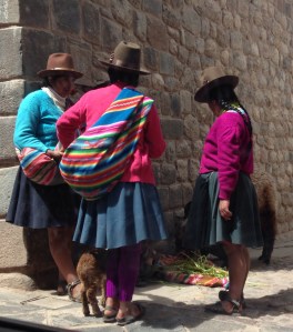 Women in traditional dress offering photos with lambs and llamas.